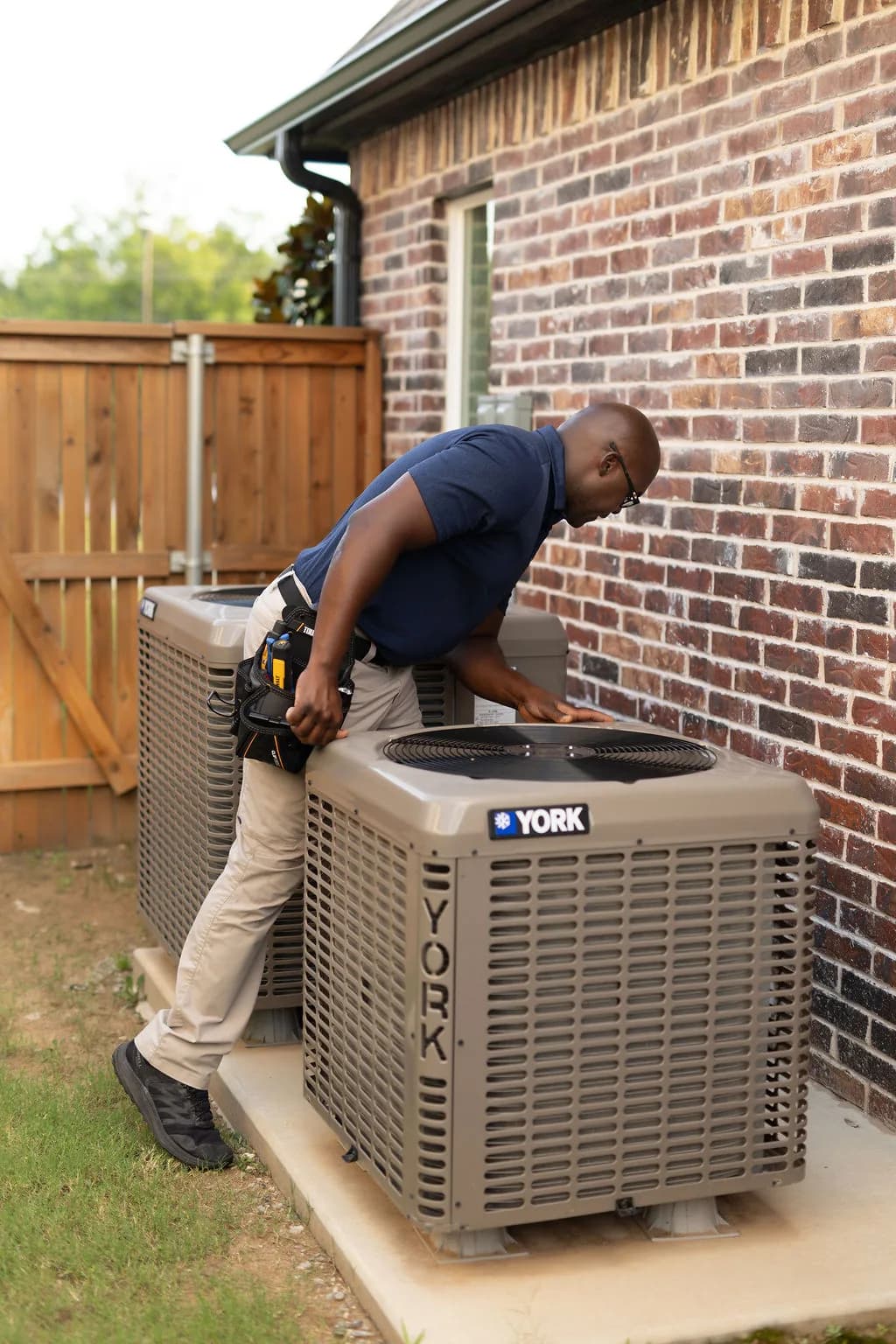 Anthonie Bounds inspecting an exterior HVAC condenser unit