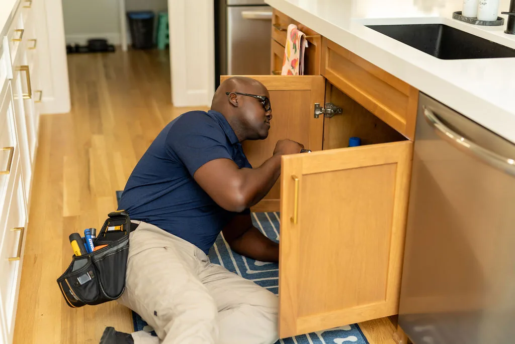 Inspecting supply lines and drains under a kitchen sink